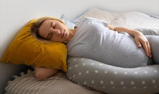 Pregnant woman sleeping comfortably on Egyptian cotton bedding with star-patterned body pillow