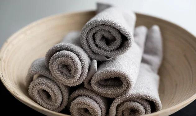 Soft gray bath towels rolled in a wooden bowl, luxury Egyptian cotton bedding