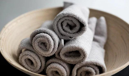 Soft gray bath towels rolled in a wooden bowl, luxury Egyptian cotton bedding