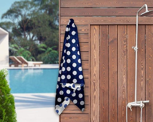 Navy blue polka dot bath towel hanging on wooden wall near poolside shower