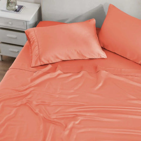 Coral Egyptian cotton bed sheets and pillowcases on a made bed, soft luxury bedding set