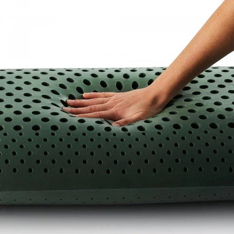 Hand pressing into green memory foam pillow with ventilation holes for comfort and support