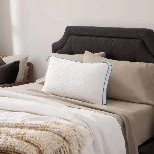 White quilted pillow with teal trim on beige bedding, luxury bedroom set