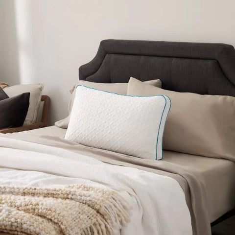 White quilted pillow with teal trim on beige bedding, luxury bedroom set