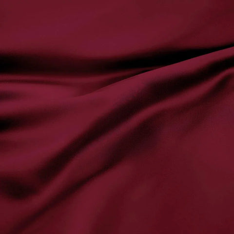 Luxury deep red Egyptian cotton bedding fabric with soft folds and rich texture