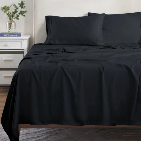 Luxury black Egyptian cotton bed sheets and pillowcases on a neatly made bed in a modern bedroom.