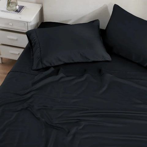 Luxury black Egyptian cotton bed sheets and pillowcases on a neatly made bed with white nightstand