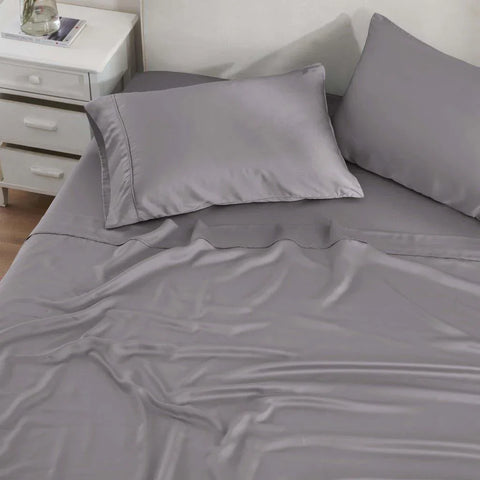 Gray Egyptian cotton bed sheets and pillowcases on a neatly made bed with white nightstand