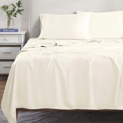 Cream Egyptian cotton bed sheets and pillowcases on a made bed, luxury bedding set