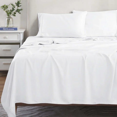 White Egyptian cotton bed sheets and pillowcases on a neatly made bed with nightstand